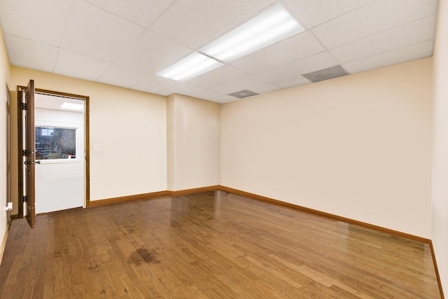 spare room featuring wood-type flooring and a paneled ceiling