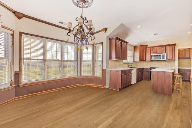 kitchen with pendant lighting, decorative backsplash, appliances with stainless steel finishes, a notable chandelier, and a kitchen island