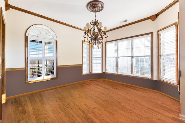 spare room with hardwood / wood-style flooring, ornamental molding, and a chandelier