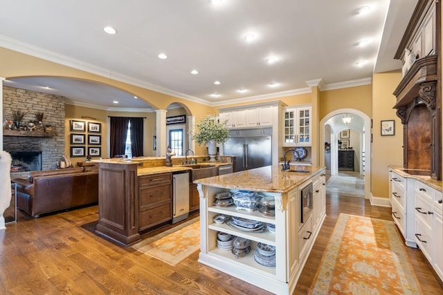 kitchen with a large island with sink, white cabinetry, stainless steel built in fridge, and light hardwood / wood-style flooring