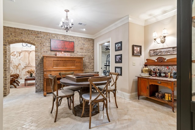 dining room featuring brick wall, ornamental molding, and ceiling fan with notable chandelier