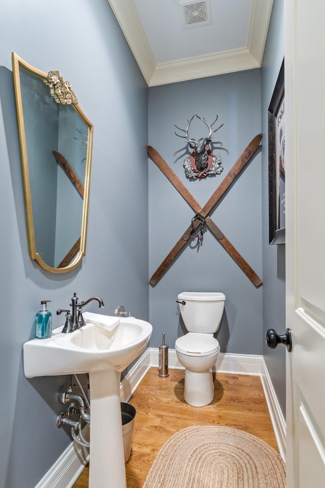 bathroom featuring wood-type flooring, ornamental molding, and toilet