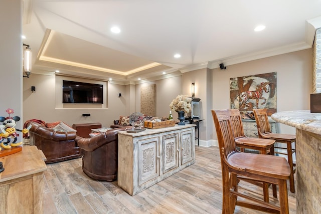 interior space featuring ornamental molding, light hardwood / wood-style floors, a raised ceiling, and a kitchen island