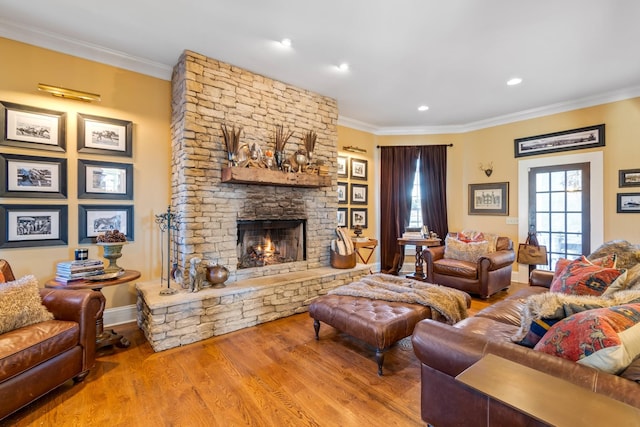 living room featuring crown molding, a stone fireplace, and light hardwood / wood-style flooring