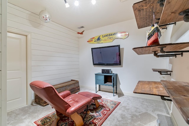 sitting room with light colored carpet and wooden walls