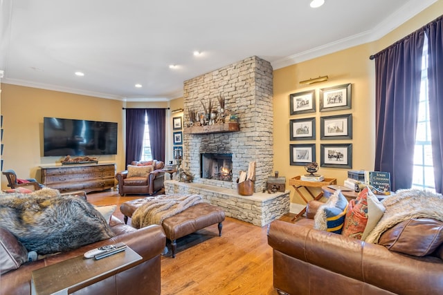 living room with crown molding, a fireplace, and light hardwood / wood-style flooring