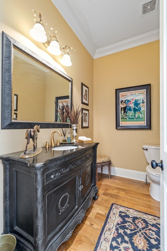 bathroom with vanity, hardwood / wood-style flooring, ornamental molding, and toilet