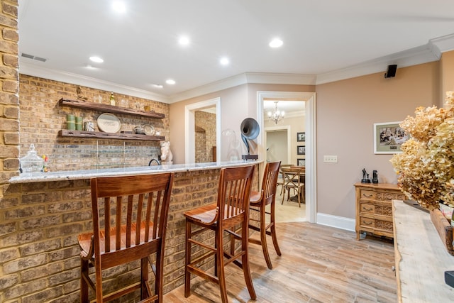 bar featuring crown molding, light hardwood / wood-style floors, and a chandelier