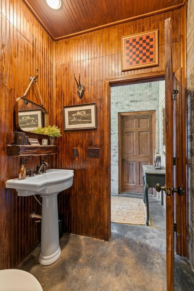 bathroom with concrete floors, wood ceiling, and wood walls