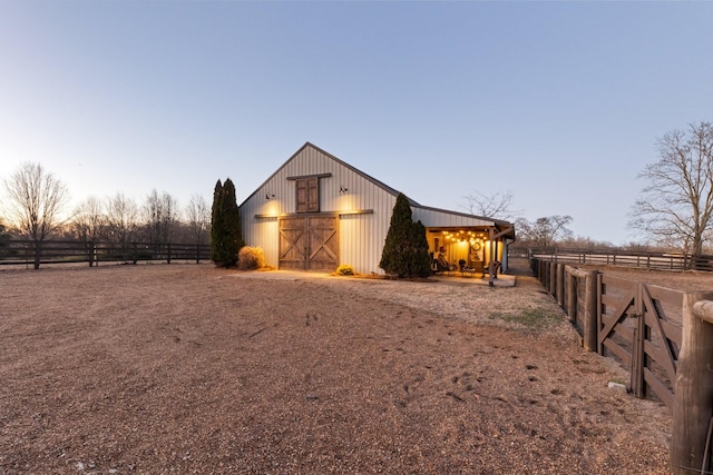 property exterior at dusk featuring an outdoor structure and a rural view