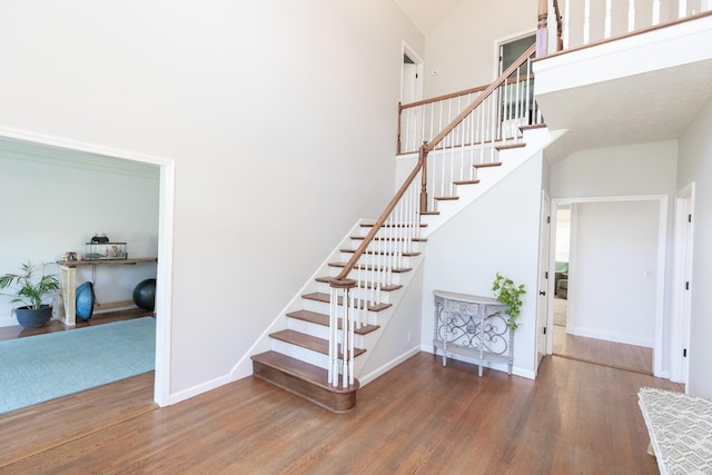 stairway with wood-type flooring and a high ceiling