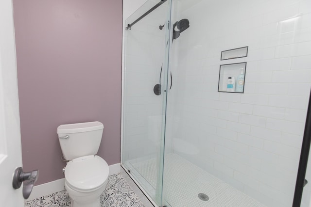 bathroom featuring tile patterned floors, a tile shower, and toilet