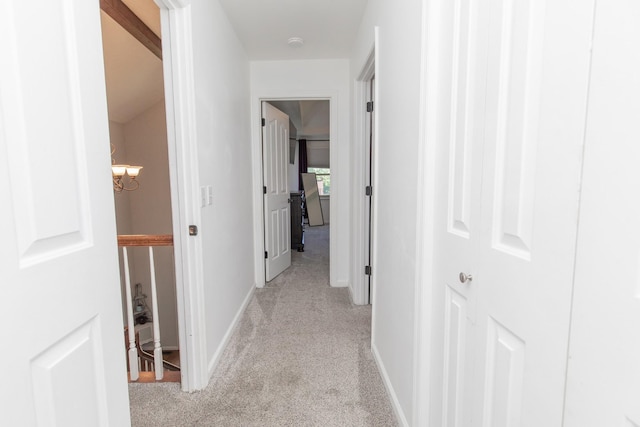 corridor with a notable chandelier and light colored carpet