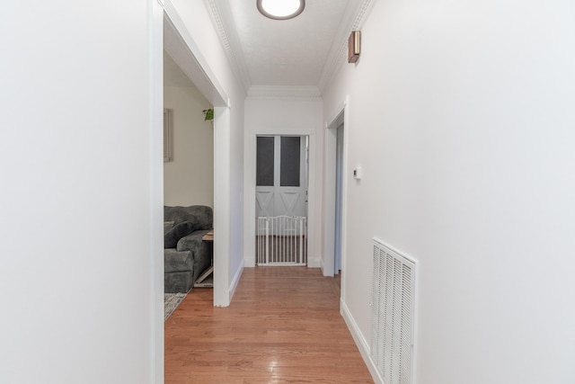 hall with light hardwood / wood-style flooring and ornamental molding