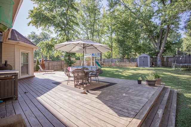 deck with a playground, a trampoline, a shed, and a lawn