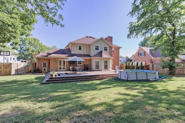 rear view of house featuring a swimming pool side deck and a lawn