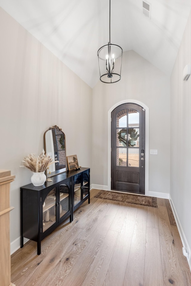 entrance foyer with vaulted ceiling, an inviting chandelier, and light hardwood / wood-style flooring