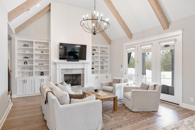 living room with a fireplace, high vaulted ceiling, light hardwood / wood-style flooring, and an inviting chandelier