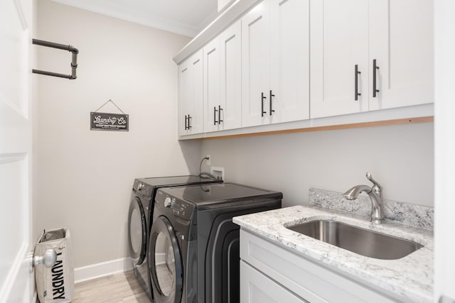 clothes washing area featuring cabinets, light wood-type flooring, ornamental molding, washer and clothes dryer, and sink