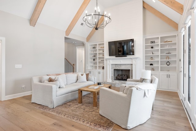 living room with light wood-type flooring, high vaulted ceiling, beamed ceiling, a fireplace, and a chandelier