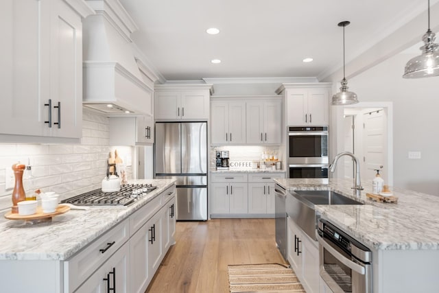 kitchen with white cabinetry, hanging light fixtures, stainless steel appliances, tasteful backsplash, and light hardwood / wood-style flooring