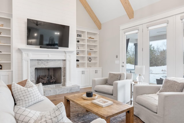 living room with a high end fireplace, hardwood / wood-style floors, vaulted ceiling with beams, and french doors