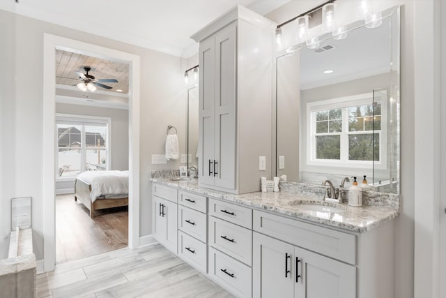 bathroom featuring a wealth of natural light, ceiling fan, vanity, and ornamental molding