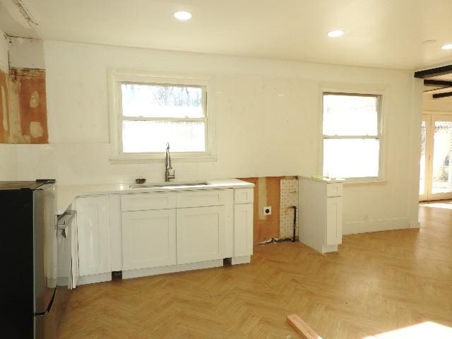 kitchen featuring white cabinets, sink, a wealth of natural light, and light parquet flooring