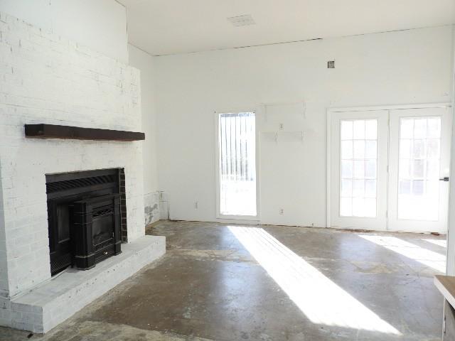 unfurnished living room with a fireplace, concrete floors, and plenty of natural light