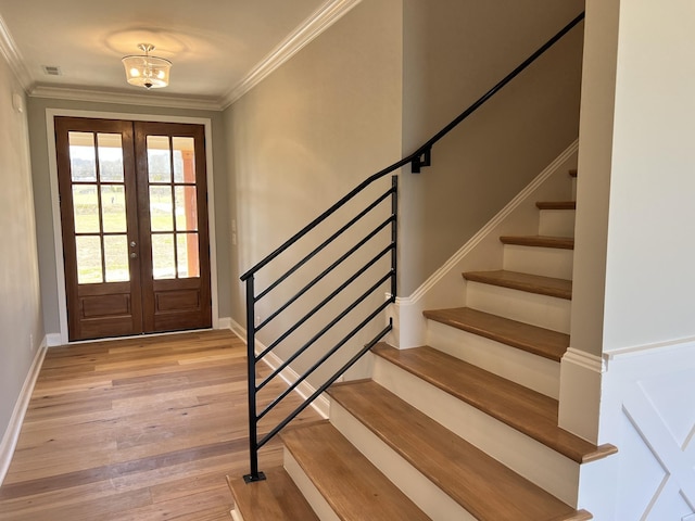 foyer entrance featuring a chandelier, light wood-type flooring, crown molding, and french doors