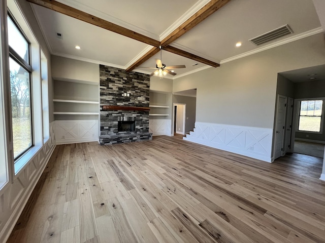 unfurnished living room featuring beamed ceiling, built in shelves, light hardwood / wood-style floors, and a fireplace