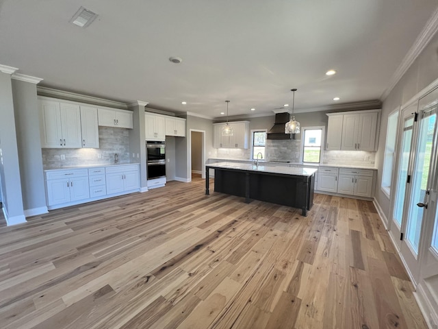 kitchen featuring pendant lighting, a spacious island, decorative backsplash, white cabinets, and custom exhaust hood