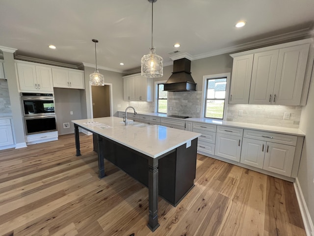 kitchen featuring decorative backsplash, a center island with sink, white cabinets, and custom range hood