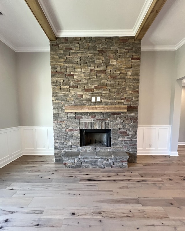 unfurnished living room with hardwood / wood-style floors, a stone fireplace, and crown molding