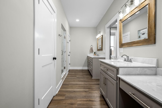 bathroom with wood-type flooring, vanity, and a shower with door