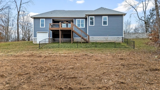 rear view of house featuring a yard, a deck, and a garage