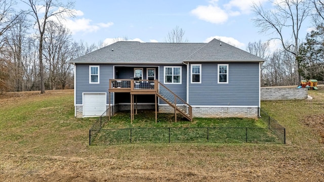 rear view of property featuring a yard, a deck, and a garage