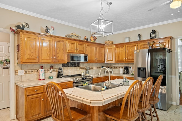 kitchen featuring appliances with stainless steel finishes, sink, light tile patterned floors, tile counters, and an island with sink