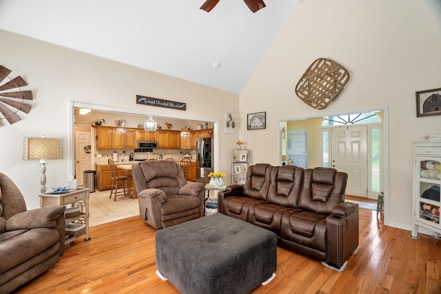 living room featuring ceiling fan, light wood-type flooring, and high vaulted ceiling