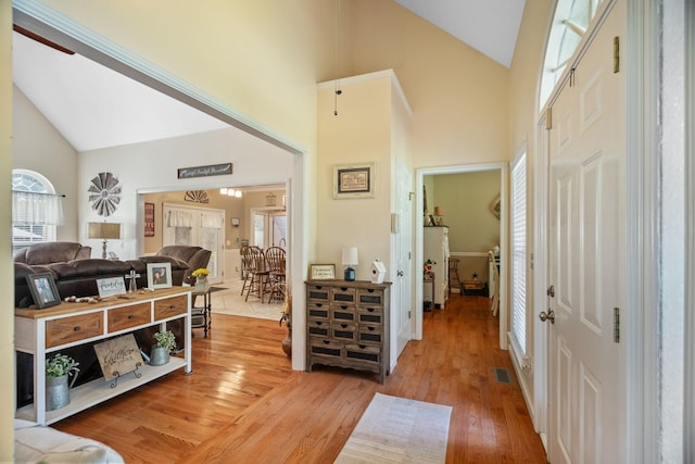 foyer entrance with high vaulted ceiling and light hardwood / wood-style floors