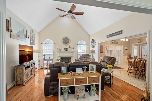 living room with light wood-type flooring, high vaulted ceiling, and ceiling fan