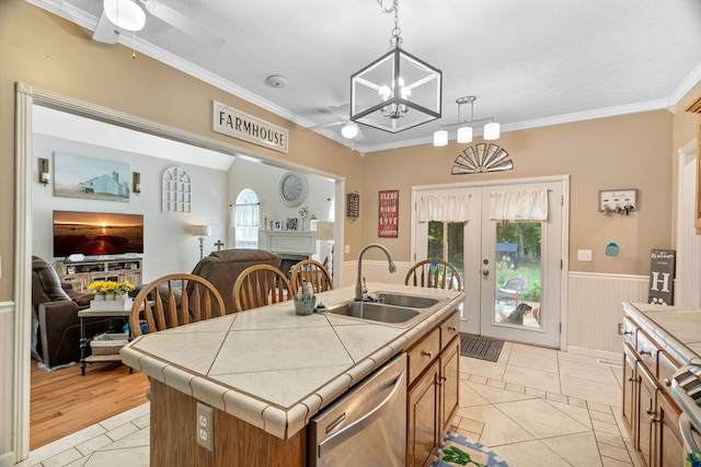 kitchen featuring dishwasher, sink, an island with sink, tile counters, and light tile patterned flooring