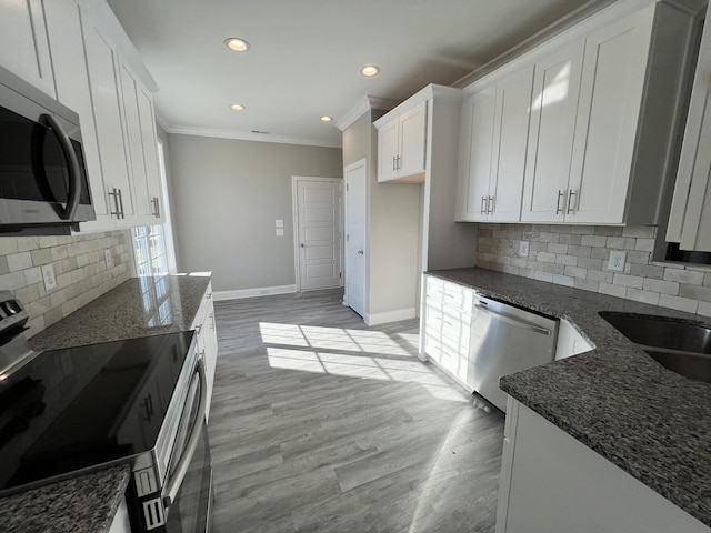 kitchen featuring dark stone countertops, white cabinetry, appliances with stainless steel finishes, and light hardwood / wood-style flooring