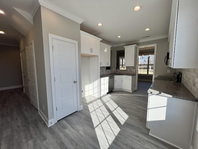 kitchen featuring tasteful backsplash, stainless steel dishwasher, crown molding, wood-type flooring, and white cabinetry