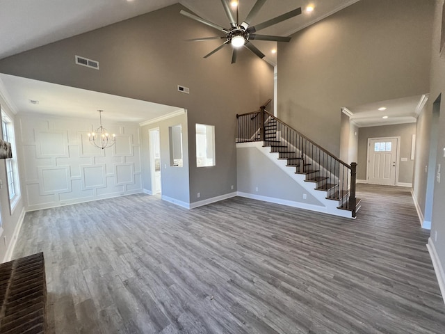 unfurnished living room with hardwood / wood-style flooring, ceiling fan with notable chandelier, ornamental molding, and high vaulted ceiling