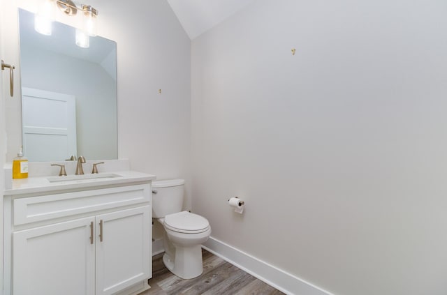 bathroom with lofted ceiling, vanity, wood-type flooring, and toilet