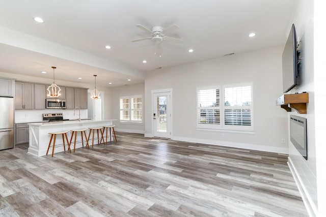 living room with ceiling fan, sink, heating unit, and light hardwood / wood-style floors