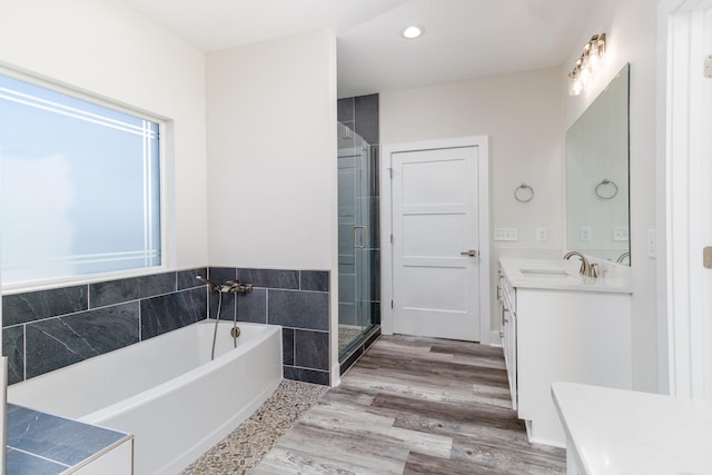 bathroom featuring wood-type flooring, vanity, and shower with separate bathtub