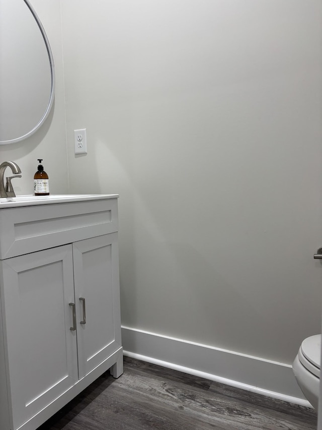 bathroom with toilet, hardwood / wood-style floors, and vanity