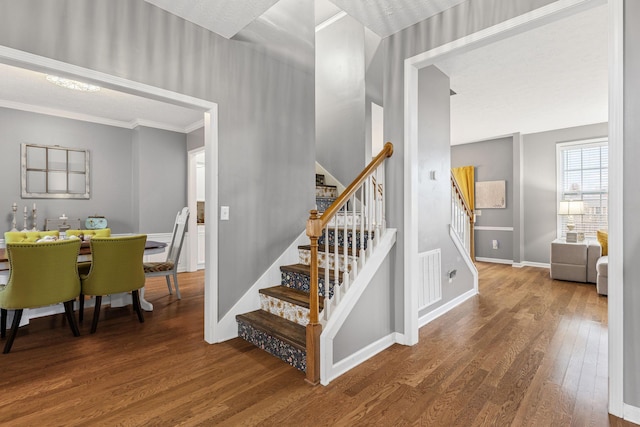 stairs featuring wood-type flooring and ornamental molding